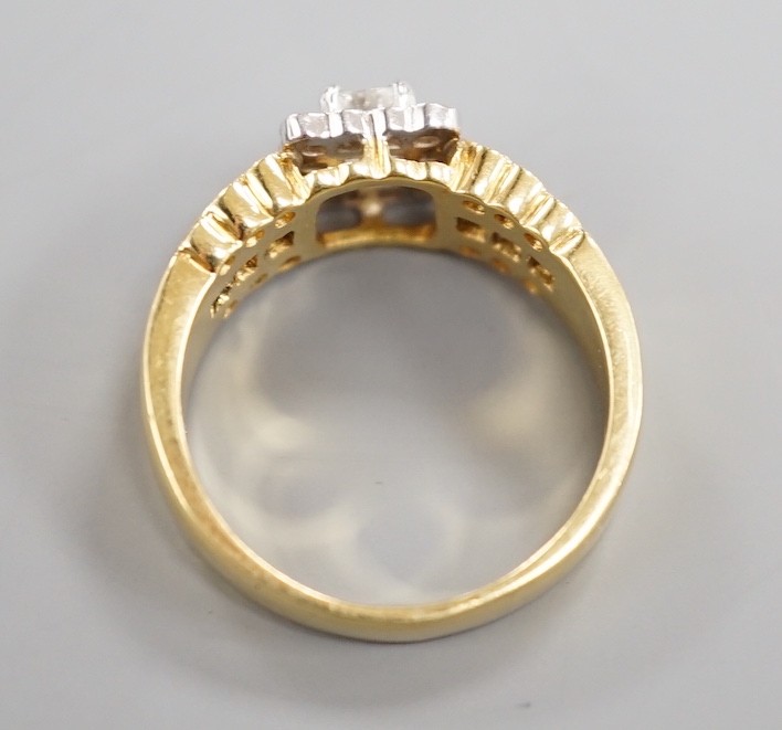A modern 18ct gold, emerald and round cut diamond set square cluster ring, three three row sapphire and diamond set shoulders, size M, gross weight 6.6 grams.